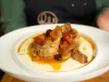 Pollo alla cacciatora succulento su un letto di polenta cremosa, guarnito con pomodorini, olive e carote.