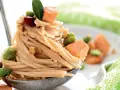 Spaghetti di riso con salmone, fave e noci, guarniti con una foglia verde. Un piatto invitante e colorato.