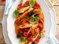 Deliziosa gallinella di mare in umido con pomodorini, olive nere e capperi, guarnita con basilico fresco.