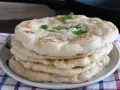 Pila di pane in padella, soffice e dorato, guarnito con erbe fresche. Perfetto per accompagnare ogni pasto.