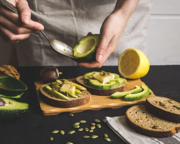Preparazione di gustose ricette con avocado: toast con avocado, formaggio e semi.