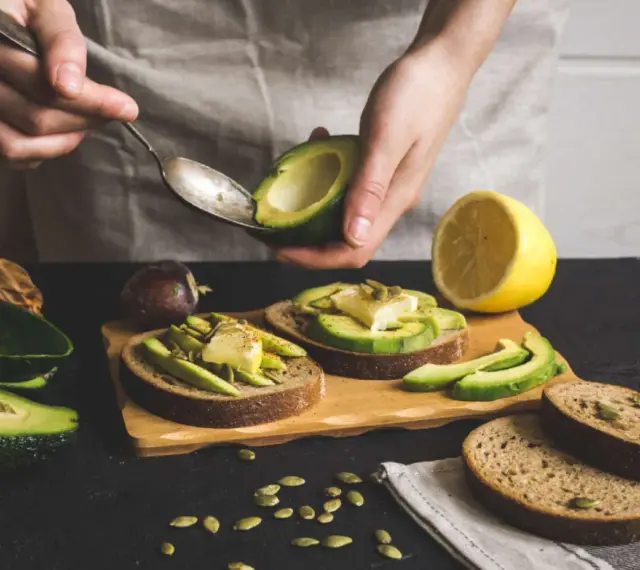 Preparazione di gustose ricette con avocado: toast con avocado, formaggio e semi.