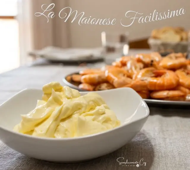 Una ciotola di maionese fatta in casa, cremosa e invitante, pronta per accompagnare un piatto di gamberi succulenti.