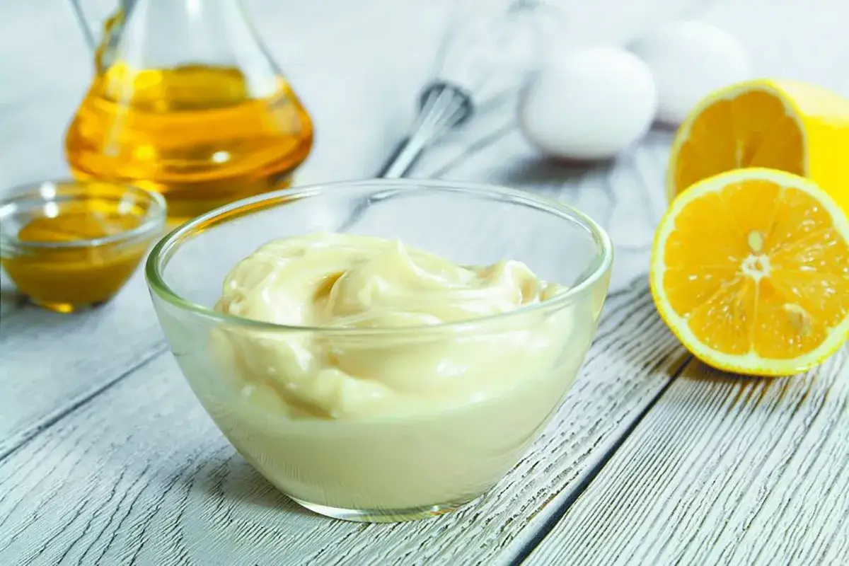 Una ciotola di cremosa maionese fatta in casa, con ingredienti freschi come limone, uova e olio.