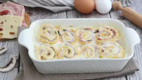 Nidi di rondine in una teglia bianca, con prosciutto, formaggio e funghi. Ingredienti per un piatto delizioso.