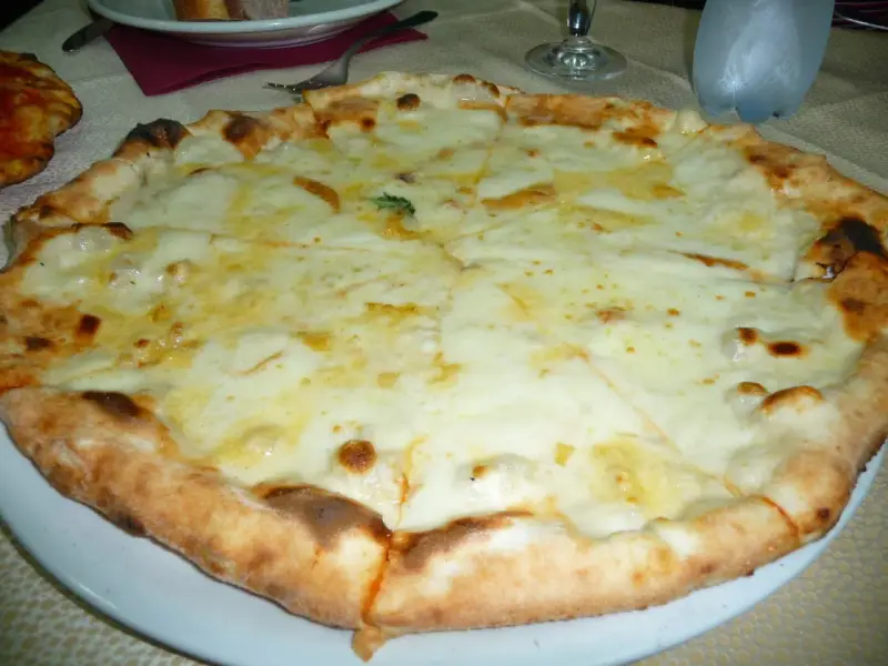 Pizza 4 formaggi appena sfornata, con crosta dorata e abbondante formaggio fuso.