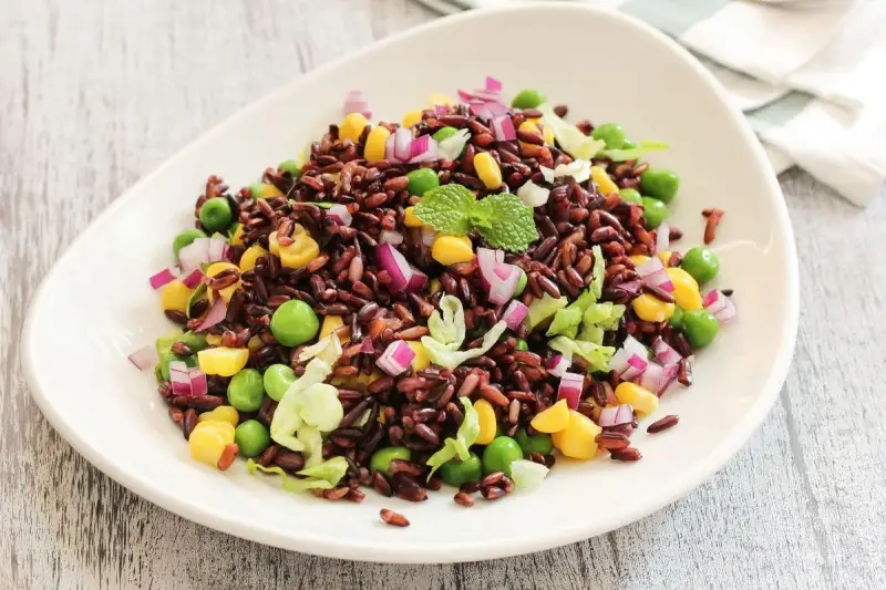 Insalata colorata con riso venere, piselli, mais, cipolla rossa e lattuga. Un'idea fresca per le tue riso venere ricette.